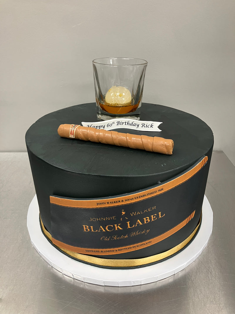 Johnnie Walker Black Label whisky bottle with a glass and a cigar on a metallic surface